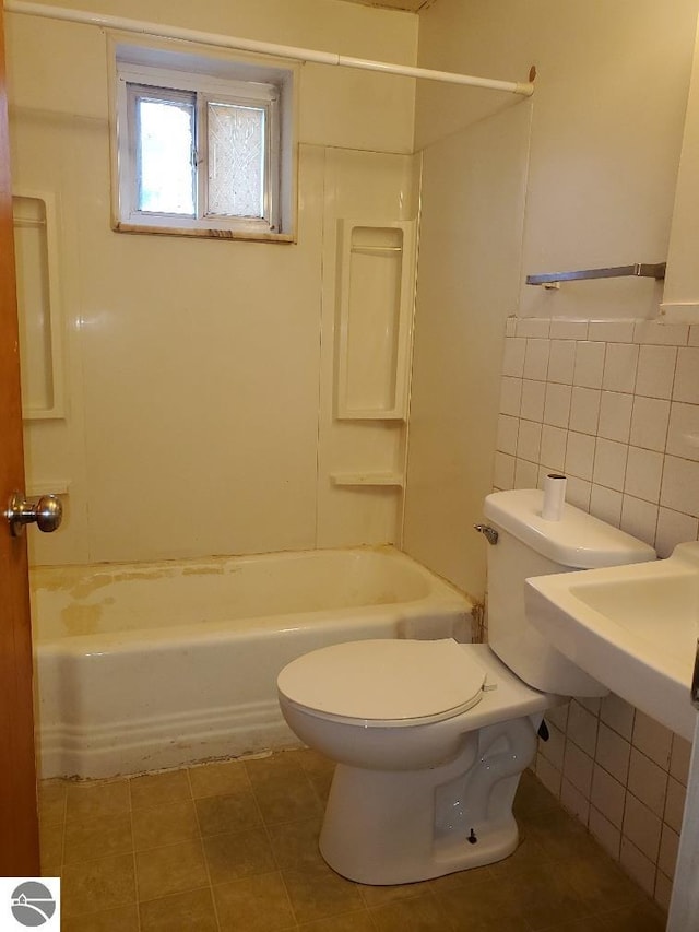 bathroom with tile patterned flooring, shower / bathing tub combination, tile walls, and toilet