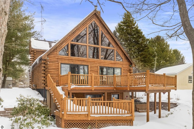 snow covered rear of property with a deck