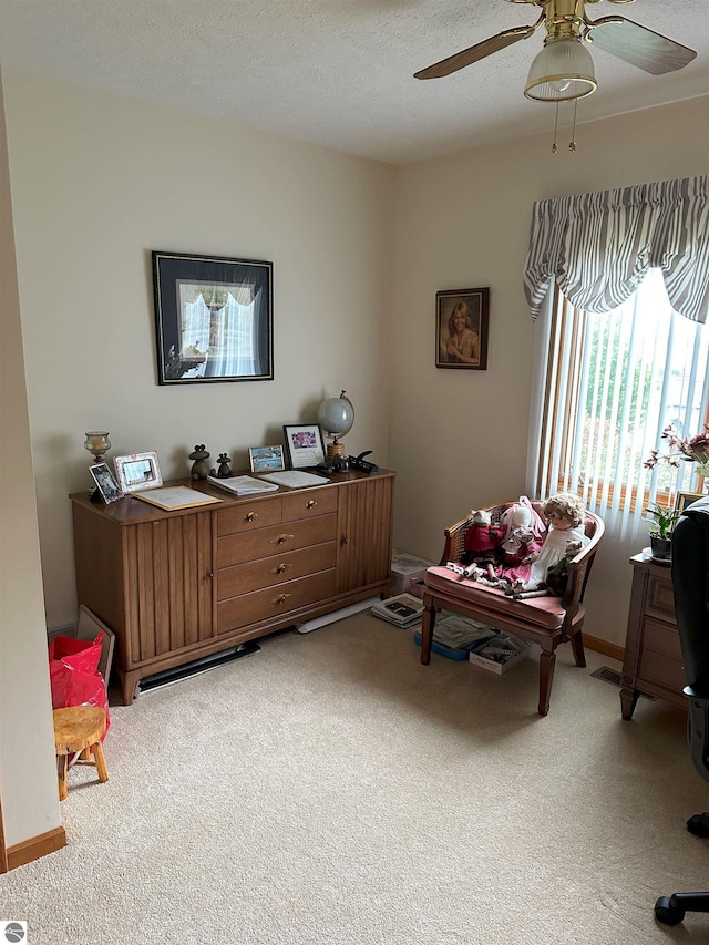 carpeted home office with a textured ceiling and ceiling fan