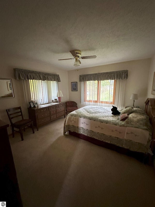 carpeted bedroom featuring ceiling fan and a textured ceiling