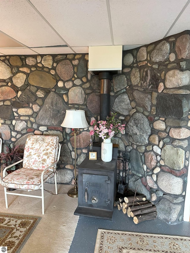 interior details featuring a drop ceiling and a wood stove