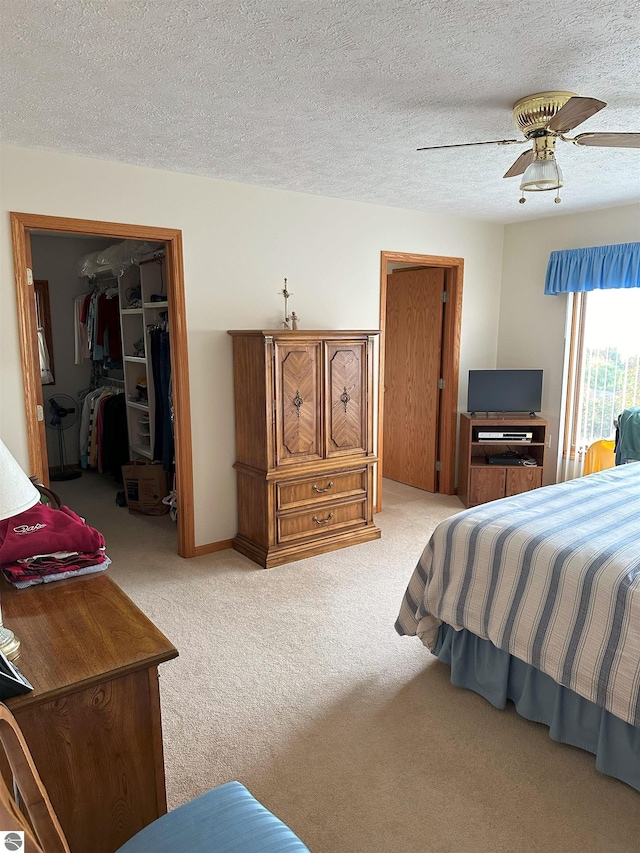 bedroom featuring light colored carpet, a textured ceiling, ceiling fan, and a closet