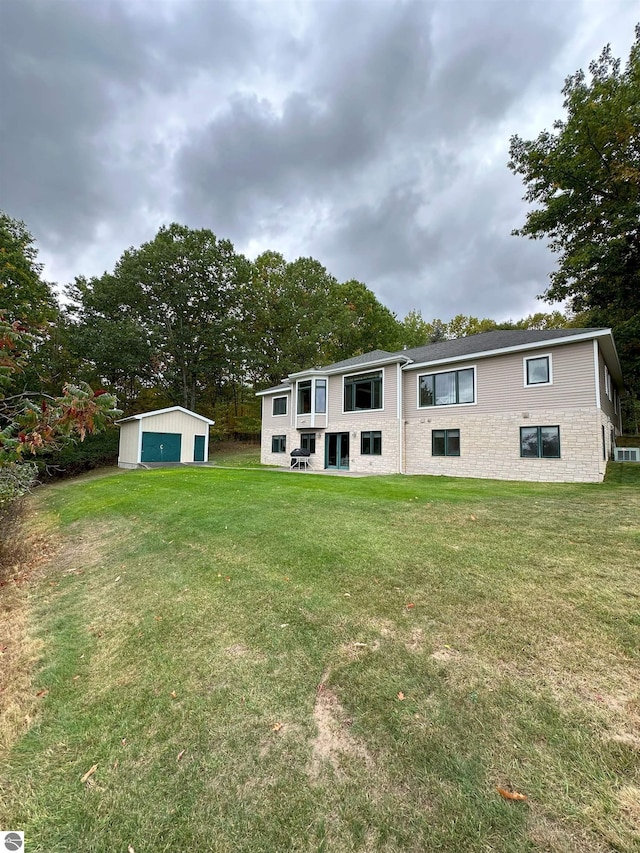 rear view of property featuring a garage, a yard, and an outbuilding