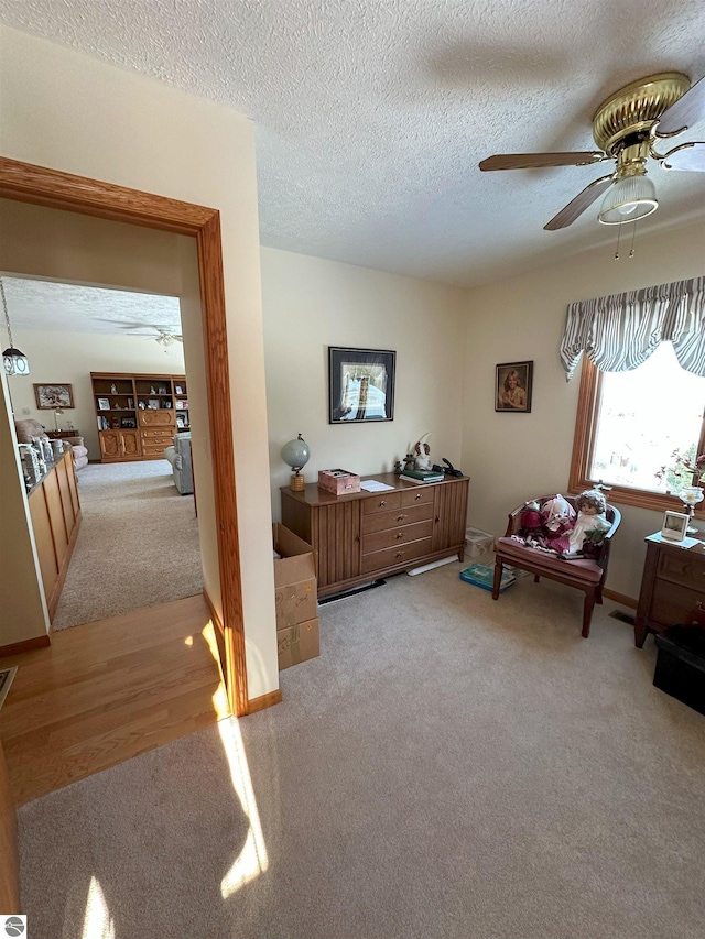 interior space with ceiling fan, light carpet, and a textured ceiling