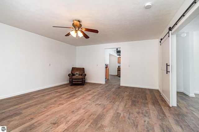 interior space with ceiling fan, a barn door, and dark hardwood / wood-style flooring