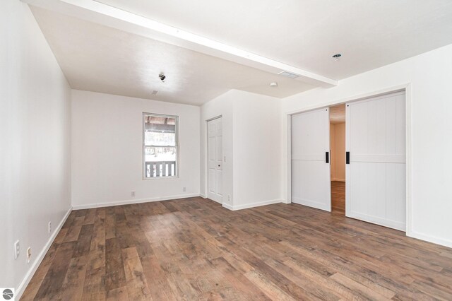 unfurnished room with beamed ceiling and dark hardwood / wood-style flooring