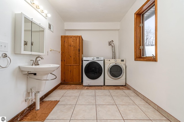 clothes washing area featuring sink, light tile patterned floors, and independent washer and dryer