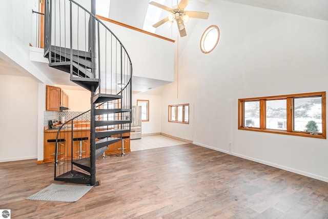 stairway featuring ceiling fan, wood-type flooring, high vaulted ceiling, and a wealth of natural light