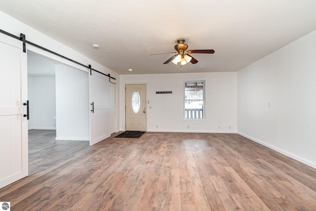 entryway with hardwood / wood-style flooring, ceiling fan, and a barn door