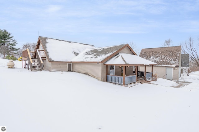 snow covered back of property with a porch