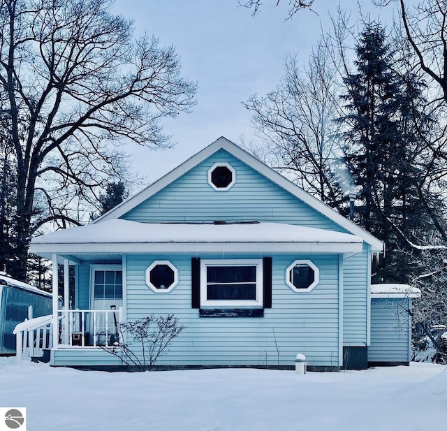 snow covered back of property with a porch