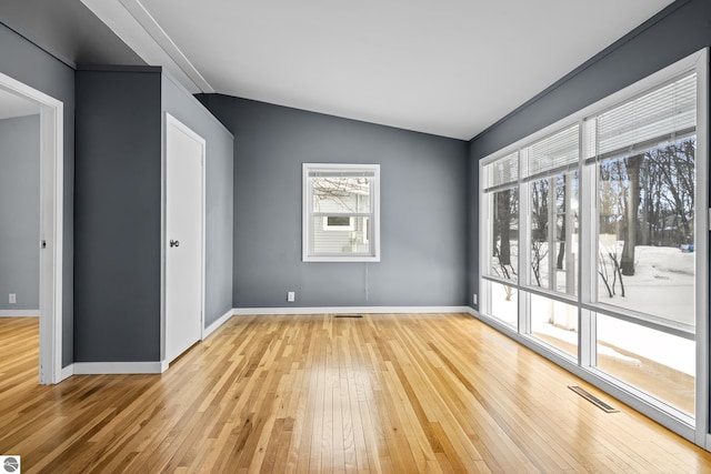 empty room featuring vaulted ceiling and light hardwood / wood-style flooring