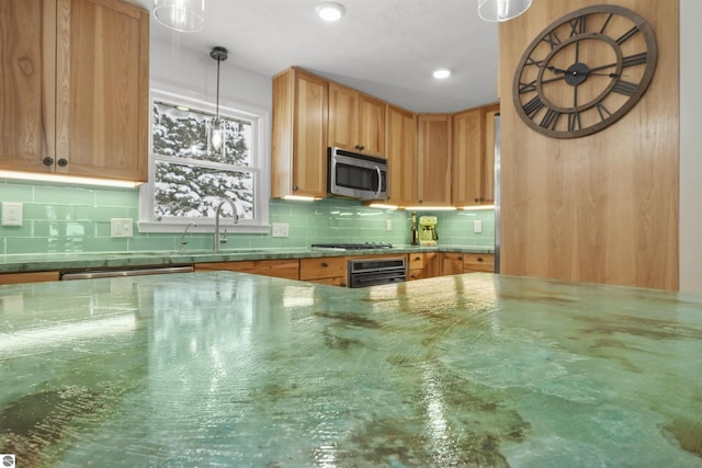 kitchen with stainless steel appliances, tasteful backsplash, hanging light fixtures, and sink