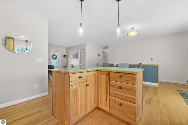 kitchen featuring decorative light fixtures, a center island, light hardwood / wood-style floors, and light brown cabinets