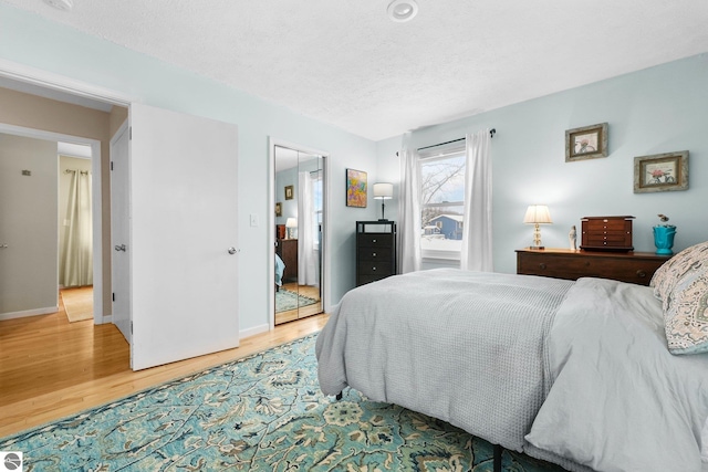 bedroom featuring wood-type flooring, a textured ceiling, and a closet