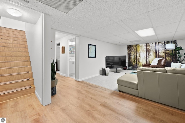 living room featuring light hardwood / wood-style flooring and a paneled ceiling