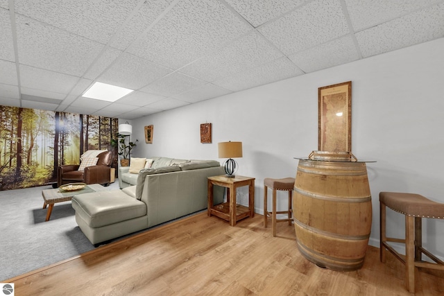 living room with light hardwood / wood-style flooring and a drop ceiling