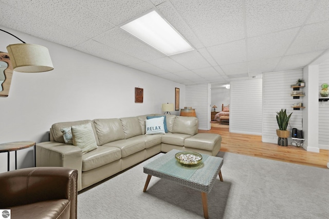 living room featuring wood-type flooring and a drop ceiling