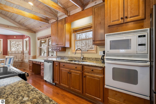 kitchen featuring lofted ceiling with beams, sink, light stone counters, dark wood-type flooring, and white appliances