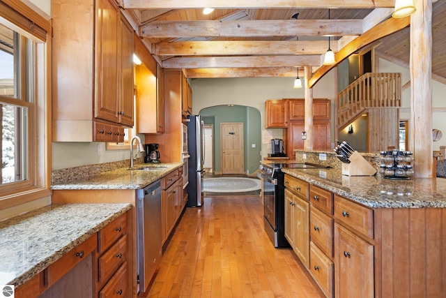 kitchen featuring stainless steel appliances, sink, light stone counters, and decorative light fixtures