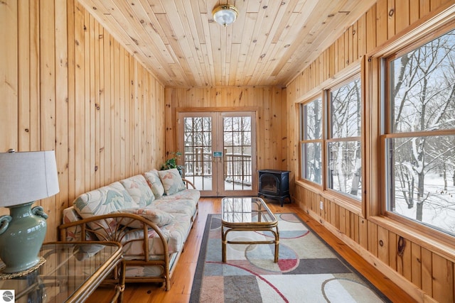 sunroom / solarium featuring french doors, plenty of natural light, a wood stove, and wooden ceiling