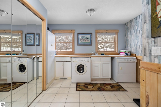 laundry room with sink, light tile patterned floors, a textured ceiling, and a wealth of natural light