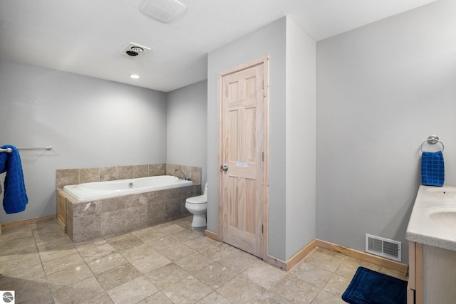 bathroom featuring tiled tub, vanity, and toilet