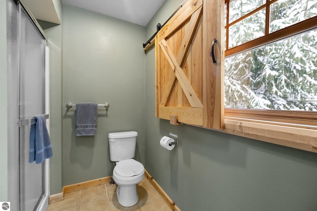 bathroom featuring a shower with door, plenty of natural light, tile patterned floors, and toilet