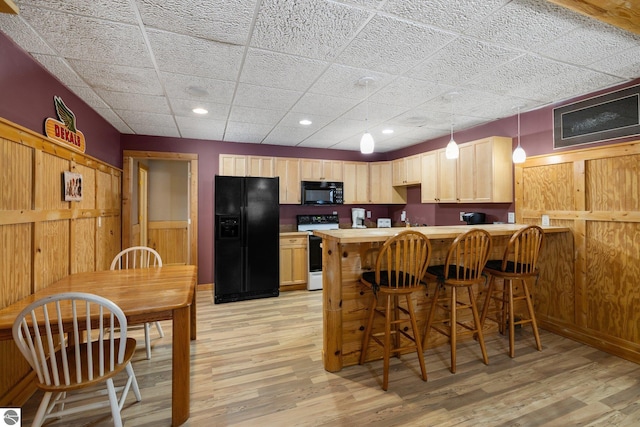 kitchen with light hardwood / wood-style flooring, light brown cabinets, kitchen peninsula, and black appliances