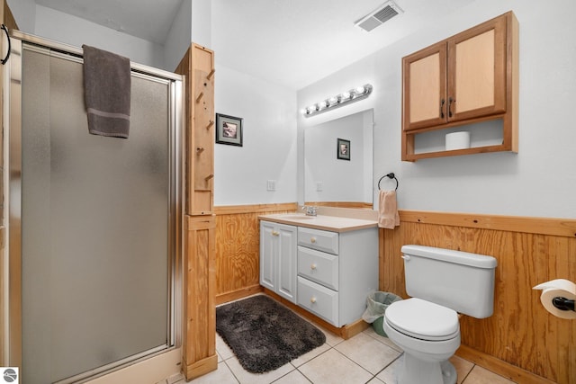 bathroom with toilet, tile patterned floors, wooden walls, and an enclosed shower