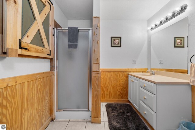 bathroom featuring an enclosed shower, vanity, tile patterned floors, and wood walls