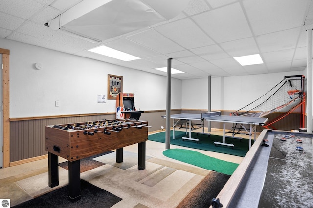 recreation room featuring wooden walls and a drop ceiling