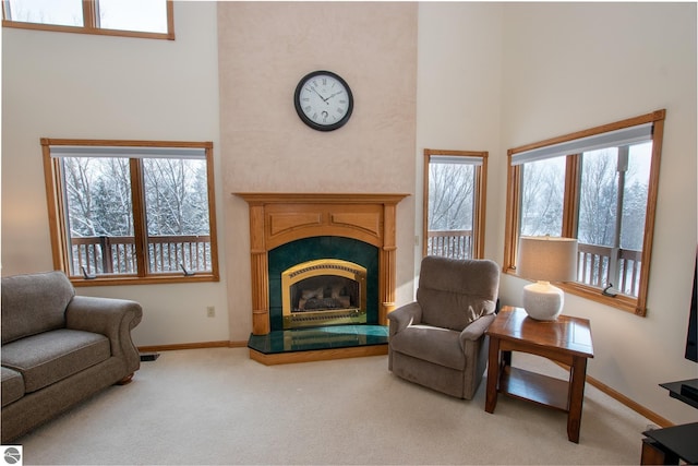 living area with a healthy amount of sunlight, carpet flooring, and a high ceiling