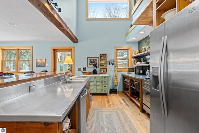 kitchen featuring stainless steel appliances, stainless steel counters, plenty of natural light, and light hardwood / wood-style flooring