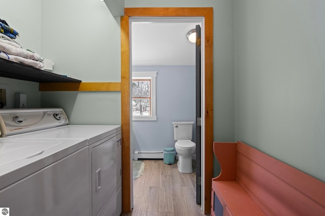 laundry room with baseboard heating, washer and clothes dryer, and light hardwood / wood-style flooring