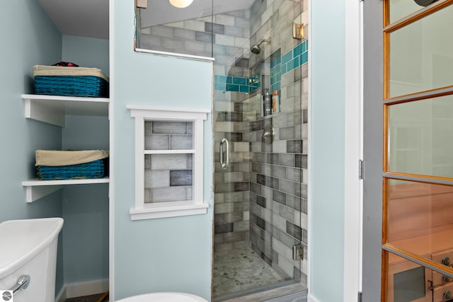 bathroom featuring a shower with door and toilet