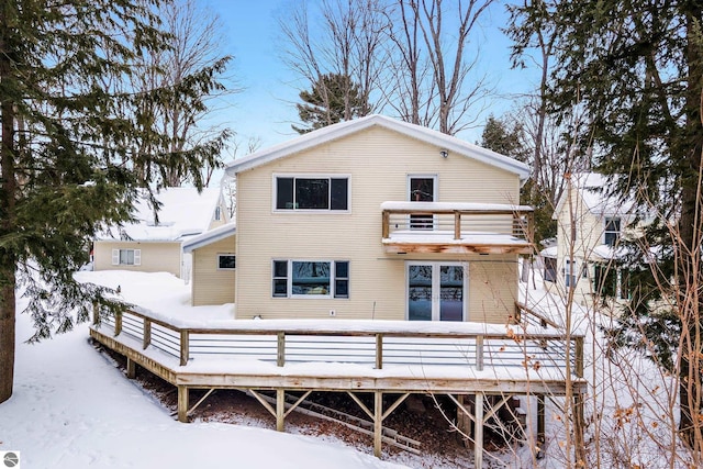 snow covered property featuring a balcony and a deck