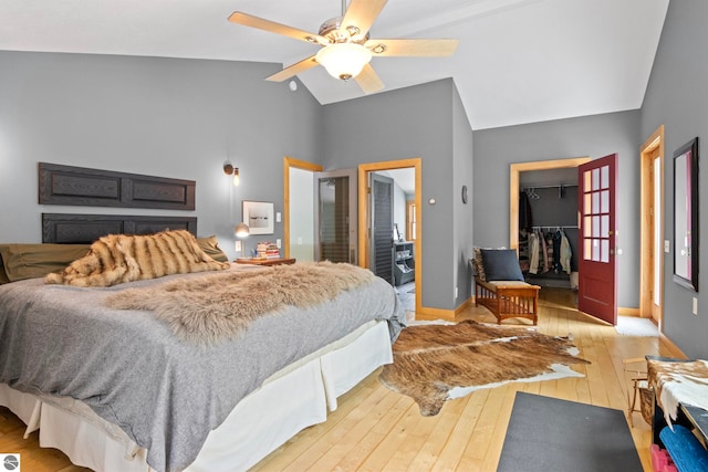 bedroom with lofted ceiling, light hardwood / wood-style flooring, ceiling fan, a walk in closet, and a closet