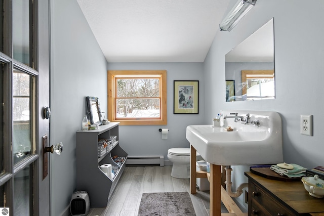 bathroom featuring a baseboard heating unit, wood-type flooring, sink, and toilet