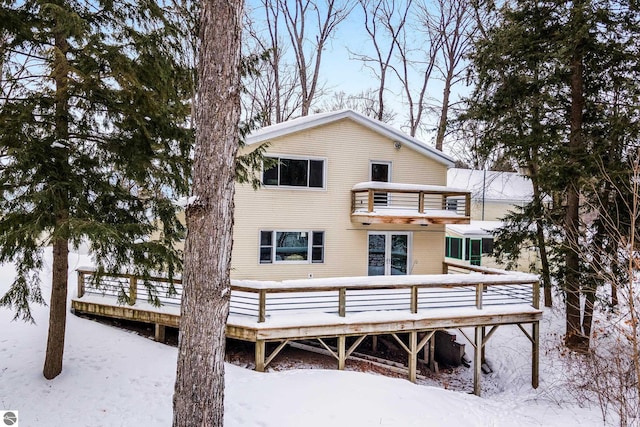 snow covered property with a wooden deck and a balcony