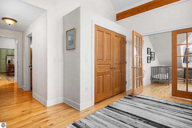 interior space featuring light hardwood / wood-style flooring, french doors, and beamed ceiling