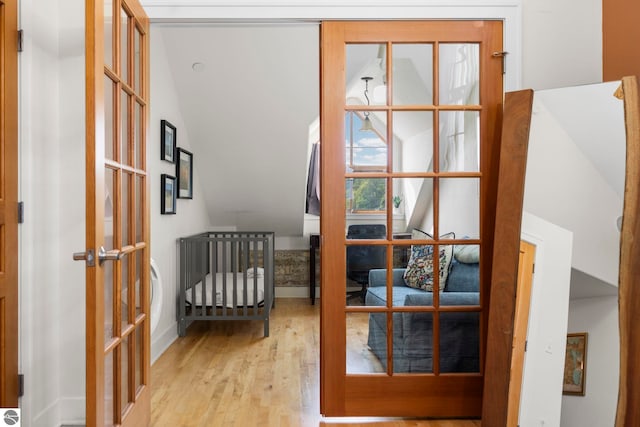 doorway with vaulted ceiling, light hardwood / wood-style floors, and french doors