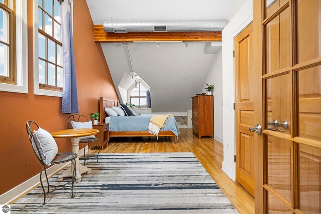 bedroom featuring lofted ceiling with beams and light wood-type flooring