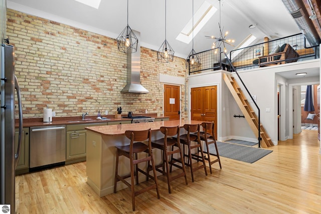 kitchen featuring decorative light fixtures, a skylight, a center island, high vaulted ceiling, and stainless steel appliances