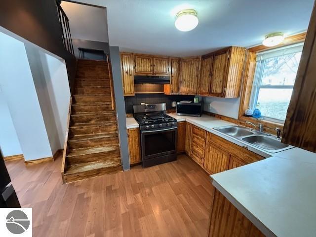 kitchen with sink, backsplash, stainless steel appliances, and light wood-type flooring