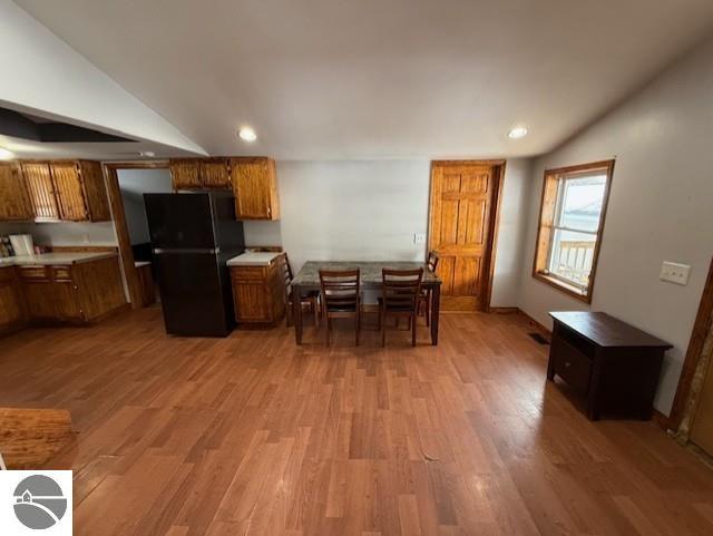 kitchen with black refrigerator, lofted ceiling, and light hardwood / wood-style flooring