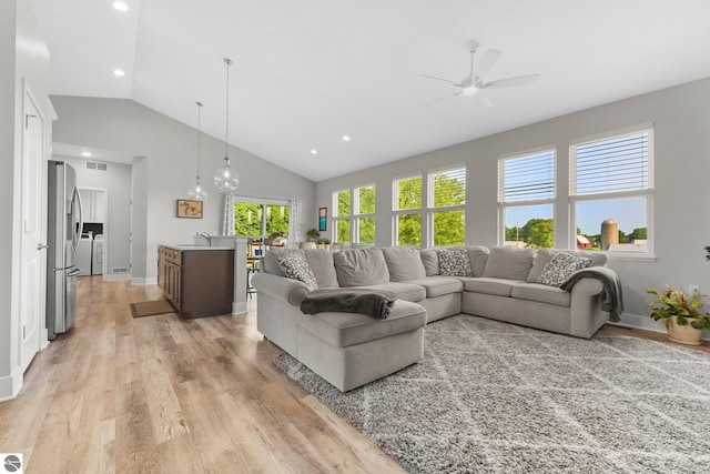 living room with ceiling fan, high vaulted ceiling, sink, and light wood-type flooring