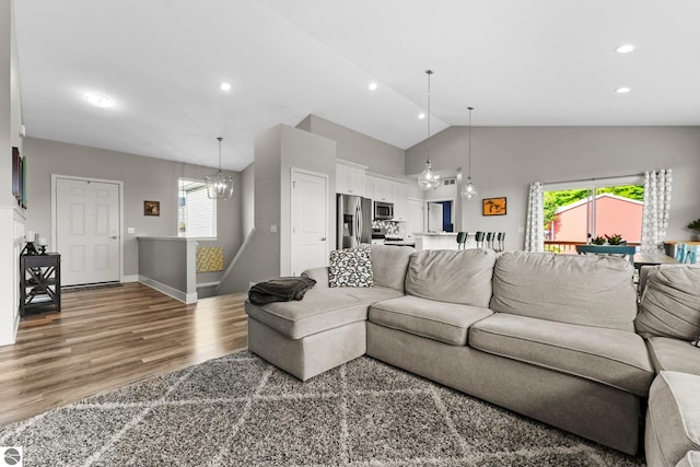 living room with hardwood / wood-style flooring, high vaulted ceiling, and a notable chandelier