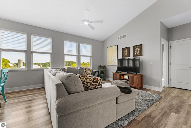 living room with high vaulted ceiling, a wealth of natural light, ceiling fan, and light hardwood / wood-style flooring