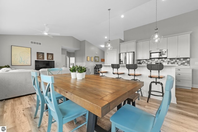 dining room with high vaulted ceiling, ceiling fan, and light hardwood / wood-style flooring